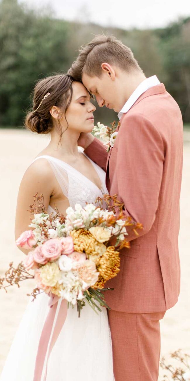 Fine Art Hochzeitsfotografie, Hochzeit Paar Shooting Braut in Hochzeitskleid mit einem Blumenstrauß, Bräutigam in einem Apricot Anzug
