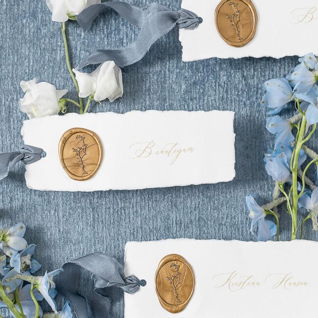 Elegante Namenskärtchen aus handgerissenes Büttenpapier mit modernen Kalligrafie mit goldenen Wachssiegeln und blauen Seidenbändern