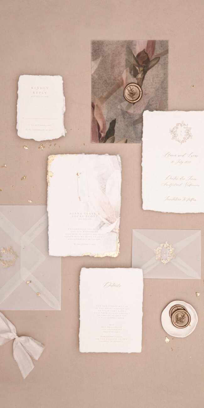 Einladung mit Detailkarte mit Hochzeitslogo und transparenten Umschläge mit goldener Heißfolienprägung und Einschlagpapier mit Magnolien und Wachssiegeln in gold