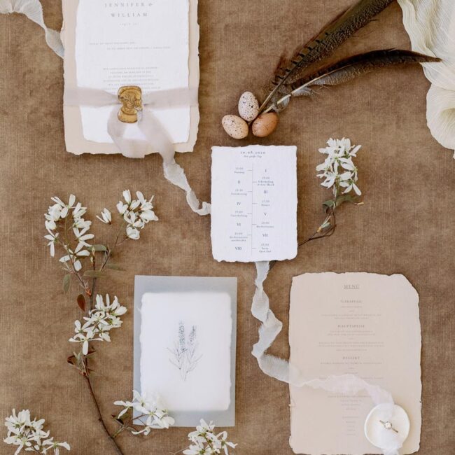 Flatlay von individuellem Einladungsset aus handgeschöpften Papier in Beige und Weiß mit Lavendel Zeichnung