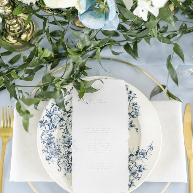 Individuelle elegante Menükarte aus handgeschöpften Papier auf einer Hochzeit in hellblau geschmückt mit blauen & weißen Blumen
