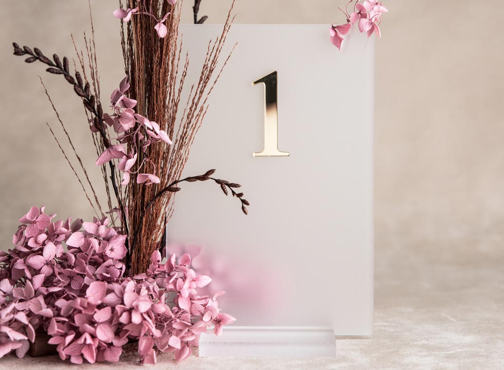 Tischnummer Schild aus Milchglas mit goldener Zahl für die Hochzeitsdeko auf dem Tisch, dekoriert mit rosa Hortensien