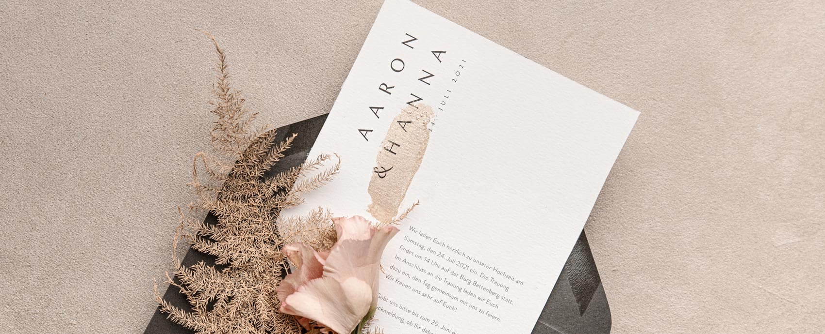 Einladungskarte zur Hochzeit mit Goldfarbe per Hand veredelt in einem grauen umschlag mit Blumen und Farn