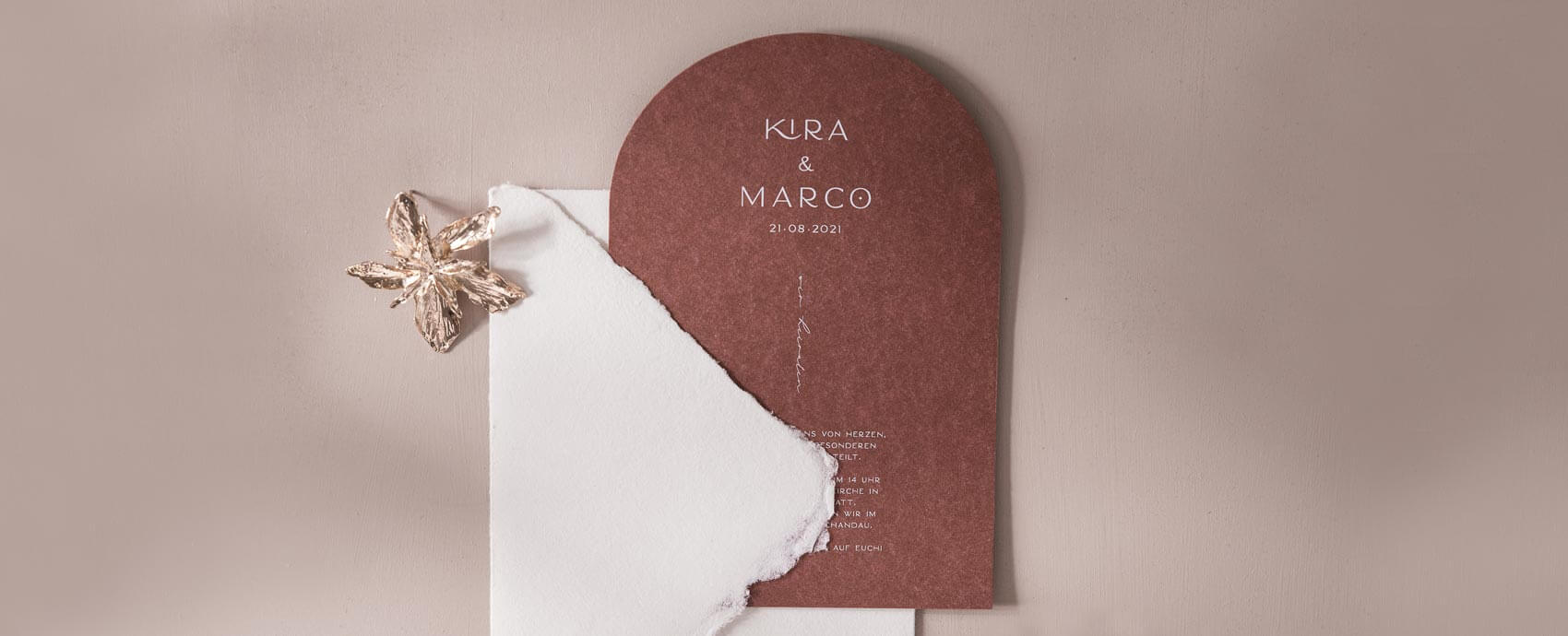 Hochzeitseinladung aus Terrakotta farbenen Papier in Torform, weiß bedruckt mit einem handgeschöpften Briefumschlag