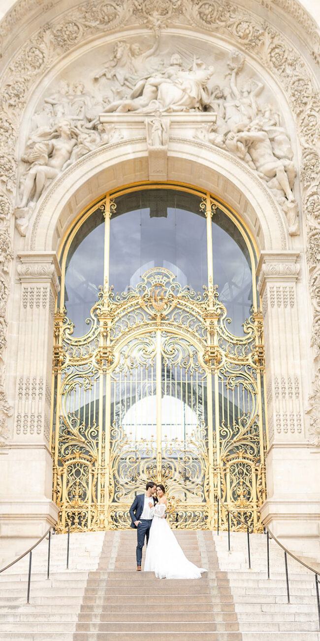 Verliebtes Brautpaar bei der Trauung in Paris am Petit Palais. Die Braut trägt ein Hochzeitskleid mit Hochzeit Blumenstrauß in Dunkelrot, Rose und Weiß