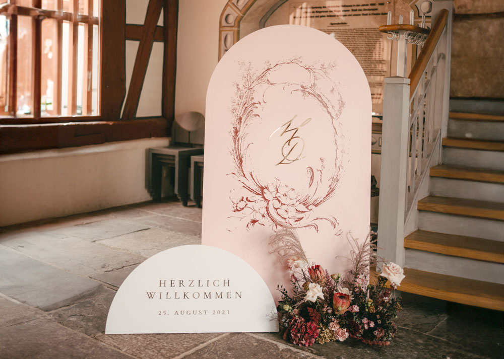 was-gehoert-zur-hochzeitspapeterie-willkommensschild-torbogen-halbrund-abgerundet-gold-dunkelrot-rosa-rose-schloss-hochzeit-verlia-papeterie