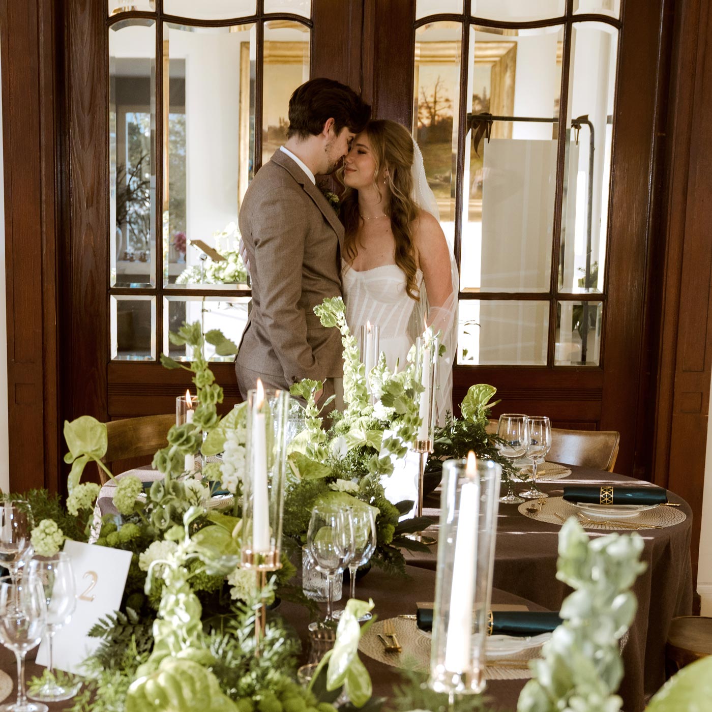 Braut und Bräutigam bei einer eleganten Hochzeit im Schloss Falkenhorst zwischen ihrer Hochzeitsdekoration mit Blumen in grün und weiß