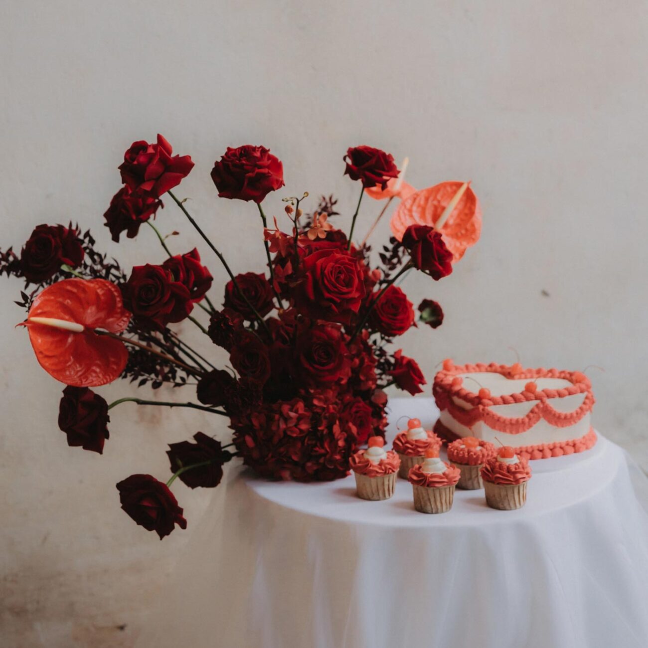 Rotes Blumenarrangement und Hochzeitstorte auf einem elegant gedeckten Tisch