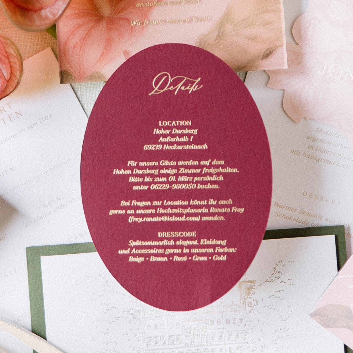 Ovale dunkelrote Detailkarte mit goldener Heißfolienprägung und Informationen zur Hochzeit im Schloss Albrechtsberg