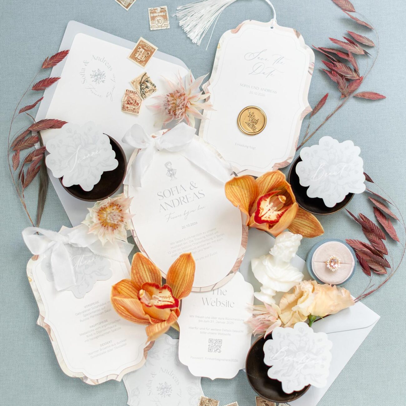 Elegantes Hochzeitseinladungsset mit ovalen Karten, Seidenband und goldenen Wachssiegeln