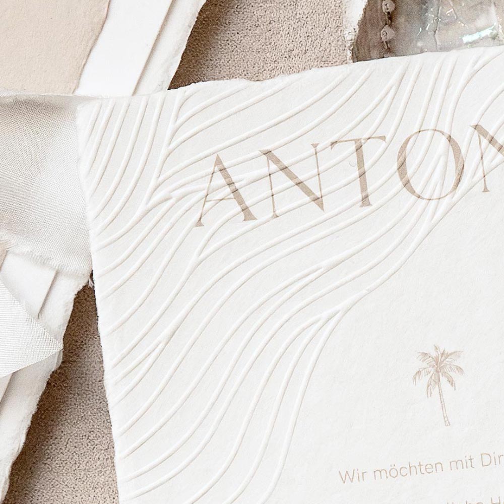 Hochprägung eines wellenartigen Musters auf einer handgeschöpften Hochzeitseinladung