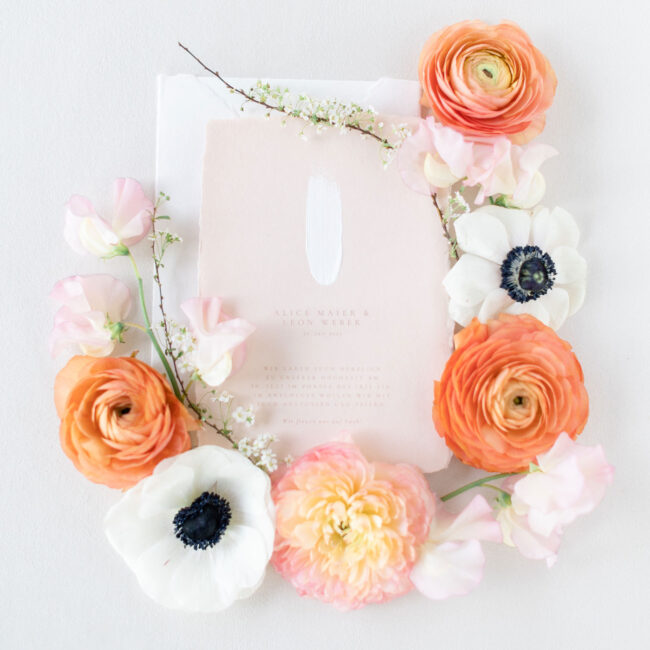 Individuelle Hochzeitseinladung aus handgeschöpftem Papier in zartem Peach mit weißem Pinselstrich und feiner Typografie