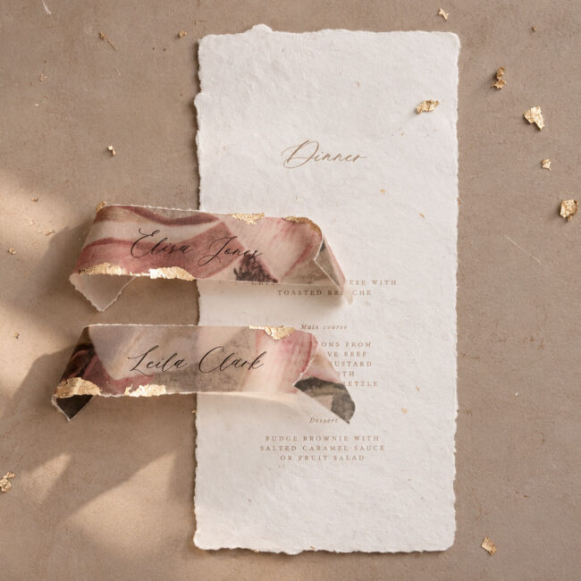 Individuelle Menükarte aus handgeschöpftem Papier mit Kalligrafieschrift und Namenskarten mit Magnolien Muster aus transparentpapier und goldenen Akzenten