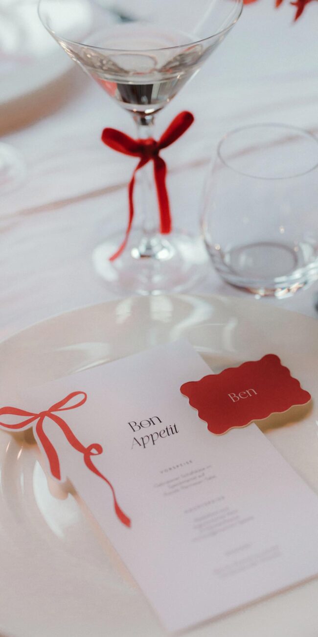 Elegante und verspielte Menükarte mit roter Schleife und passender Namenskarte